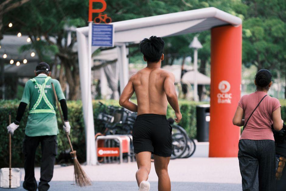Back View of a Shirtless Man Running on a Sidewalk in City